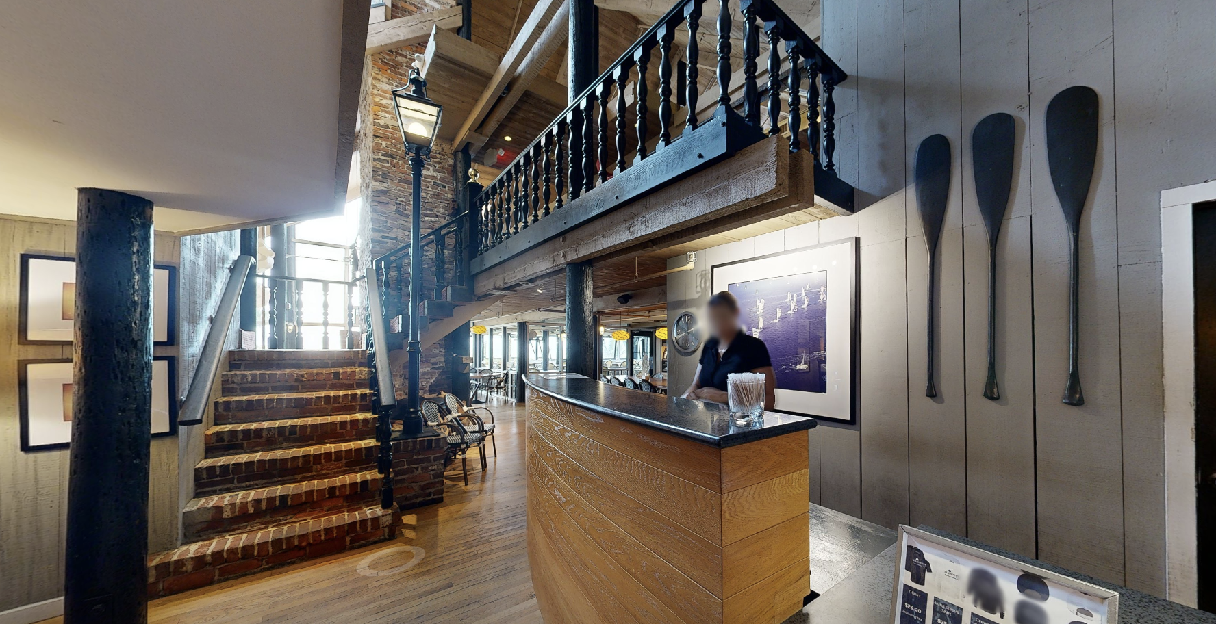 Laser-scan photo of the Sea Watch lobby and reception, showing the brick-and-timber feature staircase, turned-baluster balcony railing, host stand, and timber columns.