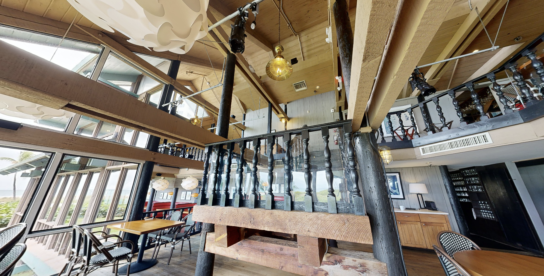 Laser-scan photo of the Sea Watch upper-level dining area, showing the timber posts, dark turned-baluster railing, exposed ceiling framing, and balcony overlooking the lower floor.